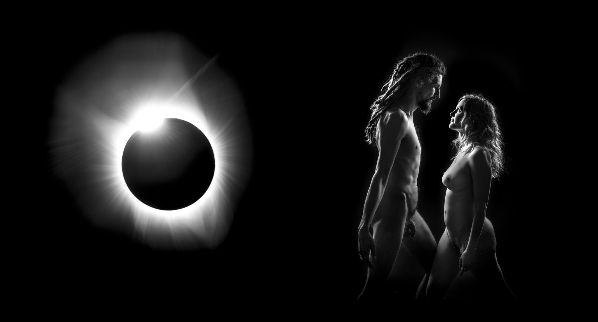 A black and white photograph of a naked man and woman face each other with arms by their side and gaze into each other eyes against a backdrop of the solar eclipse at the moment known as the wedding ring.