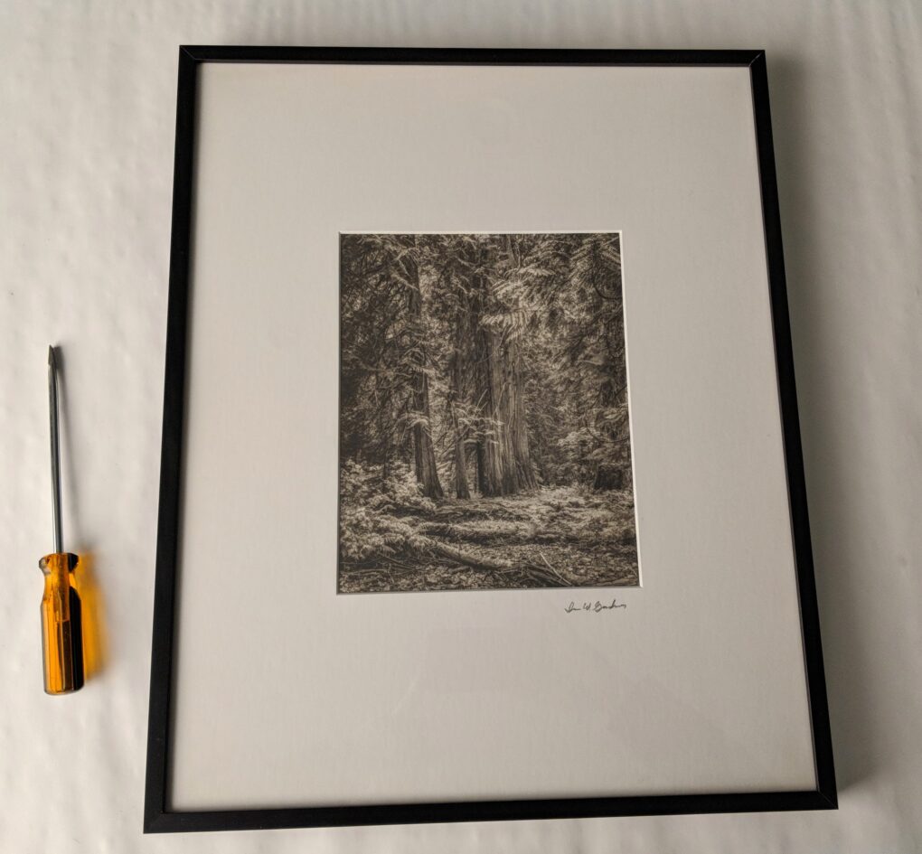 Image of a framed work of art with a screwdriver next to it.